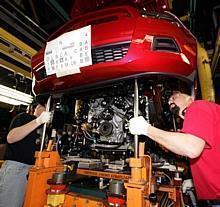 Ford workers at Auto Alliance International install an engine in the 2010 Ford Mustang. 